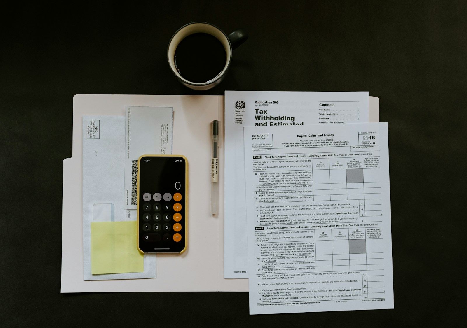 Tax forms, a phone calculator and a cup of coffee on a desk